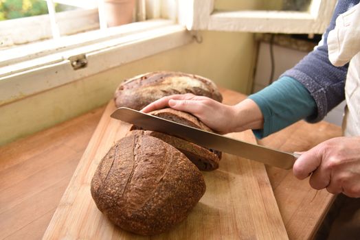 Cutting a loaf of bread into slices. Homemade bread. Healthy sour bread.