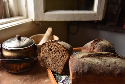 A fresh crusty loaf of homemade bread. Homemade rustic sour. Brown bread. Different types of loaves. Sliced Bread. Atmosphere image of a countryside style kitchen.