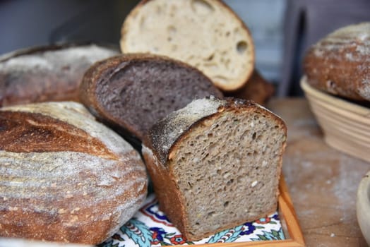 A fresh crusty loaf of homemade bread. Homemade rustic sour. Brown bread. Different types of loaves. Sliced Bread. Atmosphere image of a countryside style kitchen.