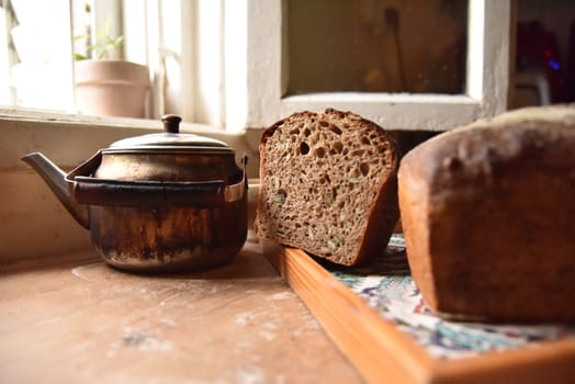 A fresh crusty loaf of homemade bread. Homemade rustic sour. Brown bread. Different types of loaves. Sliced Bread. Atmosphere image of a countryside style kitchen.