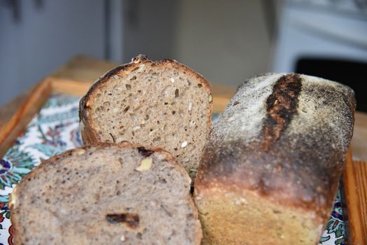 A fresh crusty loaf of homemade bread. Homemade rustic sour. Brown bread. Different types of loaves. Sliced Bread. Atmosphere image of a countryside style kitchen.