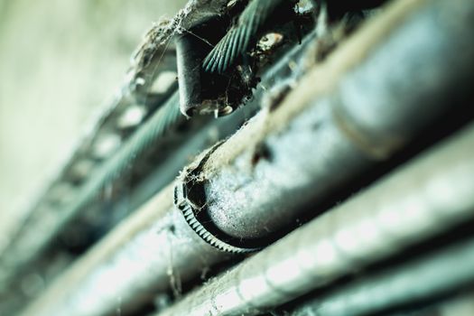 very dirty electrical cables along a dark concrete wall