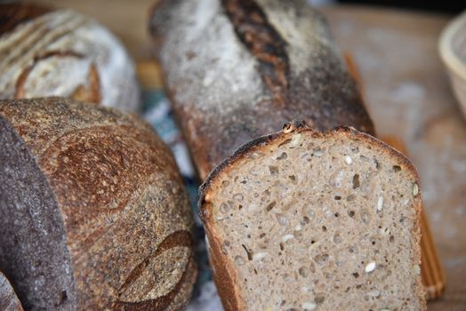 A fresh crusty loaf of homemade bread. Homemade rustic sour. Brown bread. Different types of loaves. Sliced Bread. Atmosphere image of a countryside style kitchen.