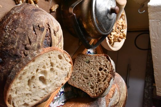 A fresh crusty loaf of homemade bread. Homemade rustic sour. Brown bread. Different types of loaves. Sliced Bread. Atmosphere image of a countryside style kitchen.
