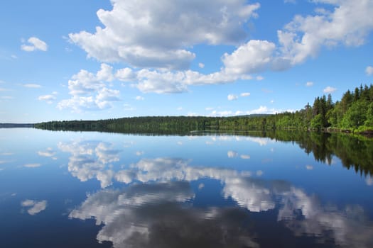 Perfect Finnish lake scenery with white clouds reflecting from calm clear water