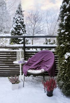 Winter feeling in snowy garden terrace- chair, blanket, table and heather decoration