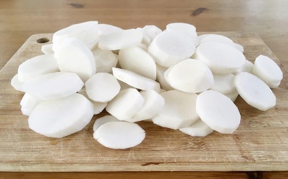 Sliced white radish on wooden butcher, preparing for making soup