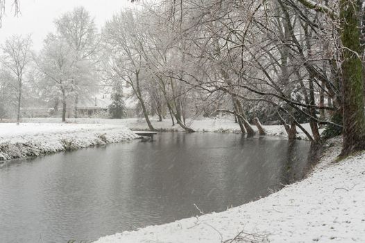 Snowfall in a park with a pond in winter, Rotterdam, Netherlands