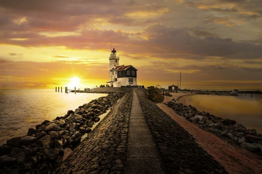 View of the white Marken island lighthouse under a sunny and cold sunrise in the early morning, Netherlands