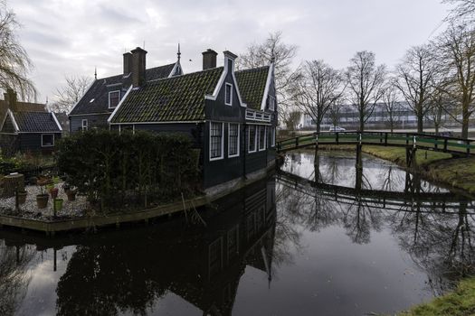 Beautiful and typical Dutch wooden houses architecture mirrored on the calm canal of Zaanse Schans located at the North of Amsterdam, Netherlands