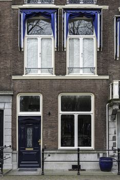 THE HAGUE, 15 March 2018 - Victorian style wooden front door and windows along a main road and protected by concrete poles and flowers pots against car parking