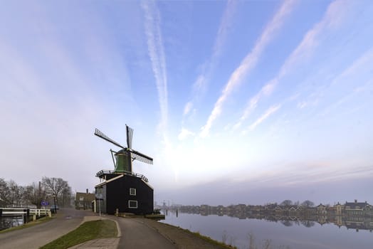 Green sawmill standing a long of the large river in the sunrise and at Zaanse Schans, Netherlands