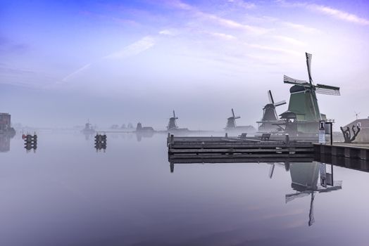 Zaanse Schans windmill reflection on the calm river water at the sunrise moment, Netherlands 