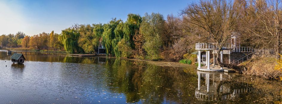 Sunny autumn evening on the blue lake with yellow trees. The Ivanki village in Cherkasy region, Ukraine