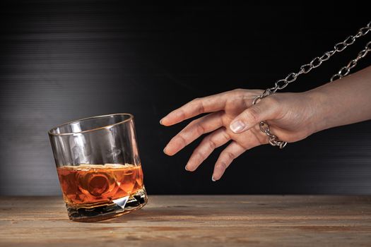 Alcoholism concept . Hands lock chain a glass of whiskey To stop drinking . Stop alcohol addiction . Addicting to alcoholic drink. 