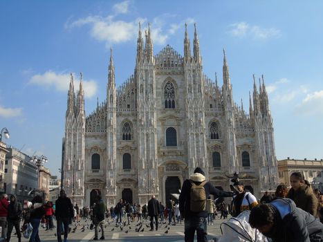 Milan, Italy - 02/01/2020: An amazing caption of the Duomo of Milan in winter days with some people enjoying the evening and beautiful coloured sky. Details of the old church from external part.