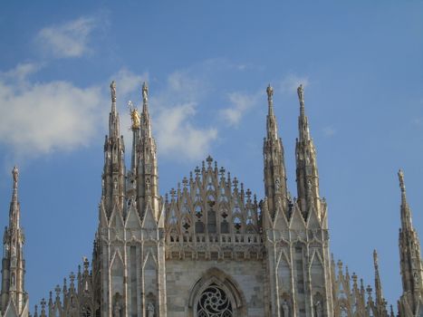 Milan, Italy - 02/01/2020: An amazing caption of the Duomo of Milan in winter days with some people enjoying the evening and beautiful coloured sky. Details of the old church from external part.