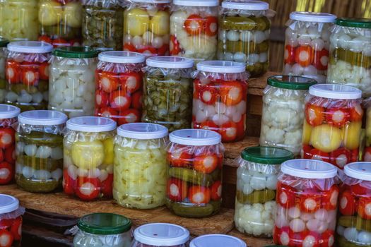 Jars with pickles, cayenne pepper, onions, cucumber and chillies