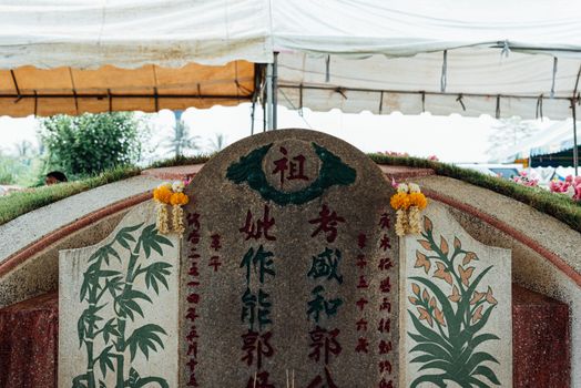 Prachinburi, Thailand - April 7, 2019 : Thai Chinese respect ancestors parents those died by food and burn fake money to sacrifice them at cemetery in Qingming Festival (Qing Ming), Tomb-Sweeping Day