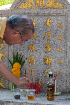 Prachinburi, Thailand - April 6, 2019 : Thai Chinese respect ancestors parents those died by food and burn fake money to sacrifice them at cemetery in Qingming Festival (Qing Ming), Tomb-Sweeping Day