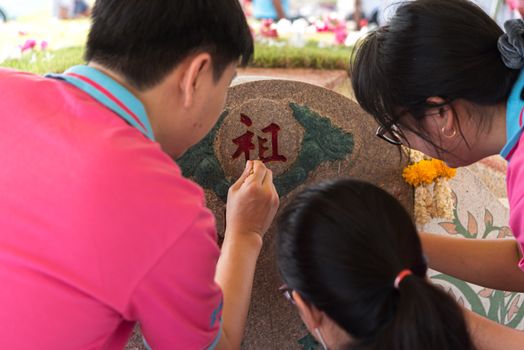 Prachinburi, Thailand - April 7, 2019 : Thai Chinese respect ancestors parents those died by food and burn fake money to sacrifice them at cemetery in Qingming Festival (Qing Ming), Tomb-Sweeping Day