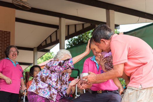 Ang Thong, Thailand - April 7, 2019 : Unidentified Asian people bathe respectation to elderly parents by water with jasmine, rose flower and aromatherapy in bowl in Songkran Festival (Thai New Year)