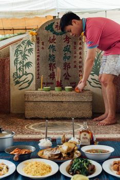 Prachinburi, Thailand - April 7, 2019 : Thai Chinese respect ancestors parents those died by food and burn fake money to sacrifice them at cemetery in Qingming Festival (Qing Ming), Tomb-Sweeping Day