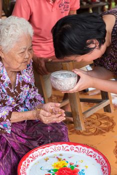 Ang Thong, Thailand - April 7, 2019 : Unidentified Asian people bathe respectation to elderly parents by water with jasmine, rose flower and aromatherapy in bowl in Songkran Festival (Thai New Year)