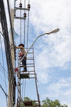 Bangkok, Thailand - June 26, 2016 : Unidentified electricians or handyman or worker risk working to install electric line on high pole by scaffolding on pickup truck at Bangkok Thailand.