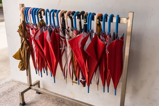 Red umbrellas hanging on the row.Many umbrellas hanging on white rail for people use.