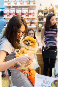 Bangkok, Thailand - July 2, 2016 : Unidentified asian dog owner with a dog feeling happy when owner and  pet (The dog) on shopping cart allowed to entrance for pets expo or exhibit hall