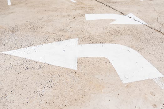 Arrow sign of turn, Old white painting on dirty concrete background.