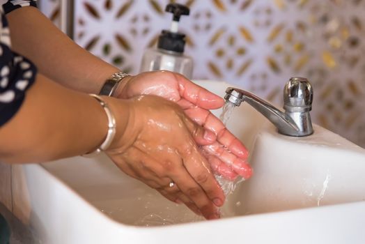 Woman use soap and washing hands under the water tap. Hygiene concept hand detail