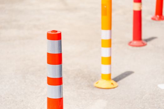 Bright orange traffic cones standing in a row on asphalt road.