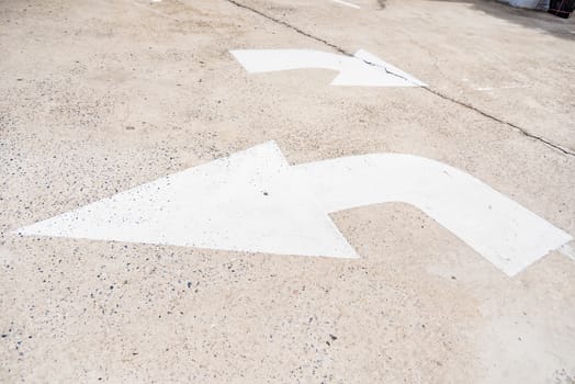 Arrow sign of turn, Old white painting on dirty concrete background.