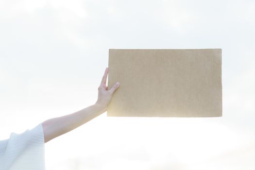 Woman's hands holding a blank banner to put the text at protesting.