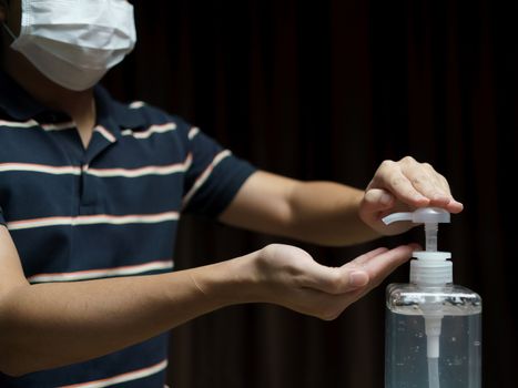 Man wear protective face mask cleaning his hands with sanitizer liquid antibacterial gel, in quarantine, corona virus concept.