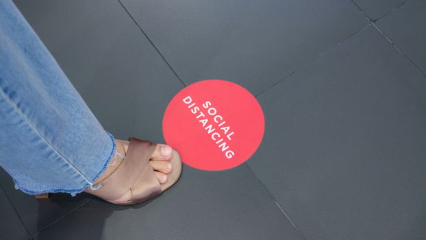 Red sign on ground, remind people to keep distance from each other to prevent spreading Coronavirus COVID-19 virus.