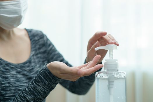 Woman wear protective face mask cleaning her hands with sanitizer liquid antibacterial gel, in quarantine, corona virus concept.