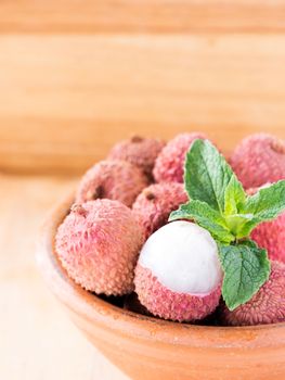 lychee fruit in clay plate on wooden background close up