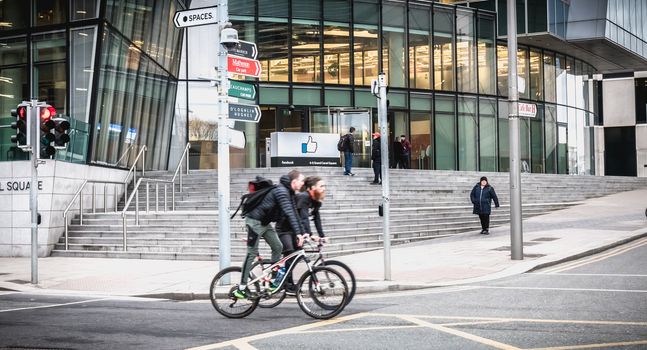 Dublin, Ireland - February 12, 2019 - cyclists passing by the Irish social seat of Facebook's international social network on a winter day
