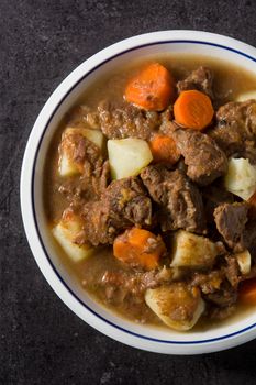 Irish beef stew with carrots and potatoes on black background