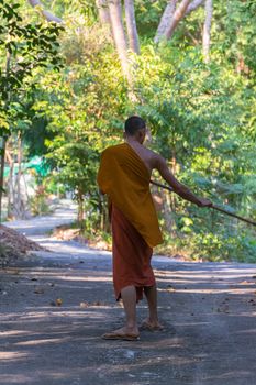 Chanthaburi, Thailand - January 1, 2016 : Thai monk sweeping a temple floor for clean at Thai forest temple (Wat Pa) in the Na Yai Am District of Chanthaburi, Thailand.