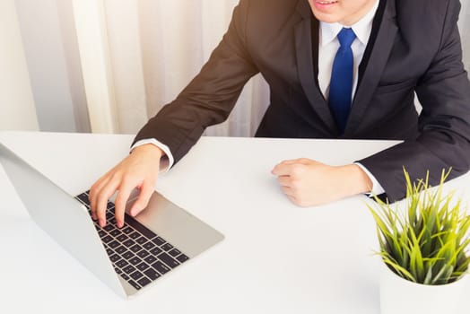 Work from home, Asian young businessman smile wearing headphones and suit video conference call or facetime with laptop computer on desk at home office