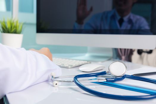 Medicine doctor's working on desk. Closeup of Stethoscope. Hand of man physician video call raise hands to greet patients on table front computer monitor at hospital office, Healthcare medic concept