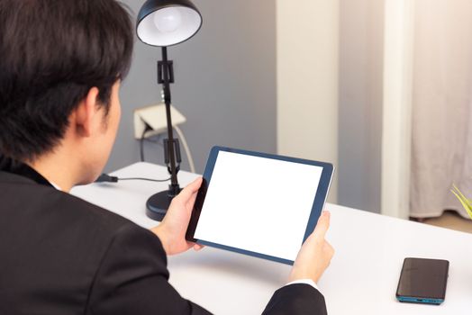 Work from home, Back view of Asian young businessman smile wearing suit video conference call or facetime by smart digital tablet computer blank screen on desk