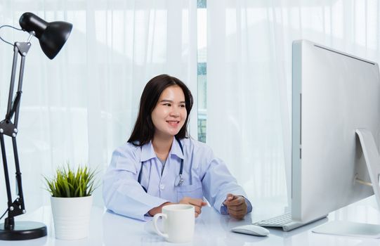 Asian young beautiful woman doctor video call conference online sit listen  patient to explain on front desktop PC computer monitor quarantines disease coronavirus or COVID-19 at hospital office