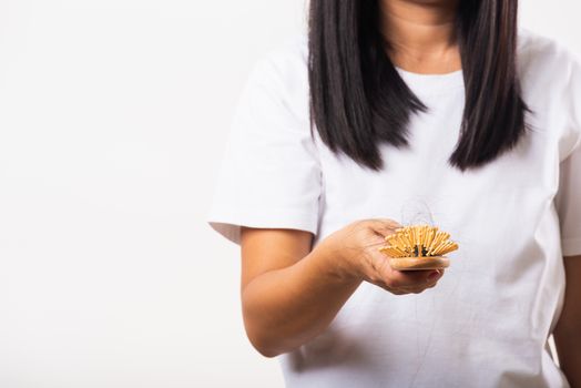 Asian woman unhappy weak hair she shows hairbrush with damaged long loss hair in the comb brush on hand, studio shot isolated on white background, medicine health care concept