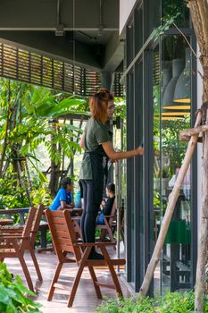 Rayong, Thailand - March 13, 2016 : Unidentified asia staff women cleaning by wipe a glass at coffee cafe in gas station preparation for services