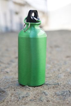 Green bottle of water in ground at rural outdoors.